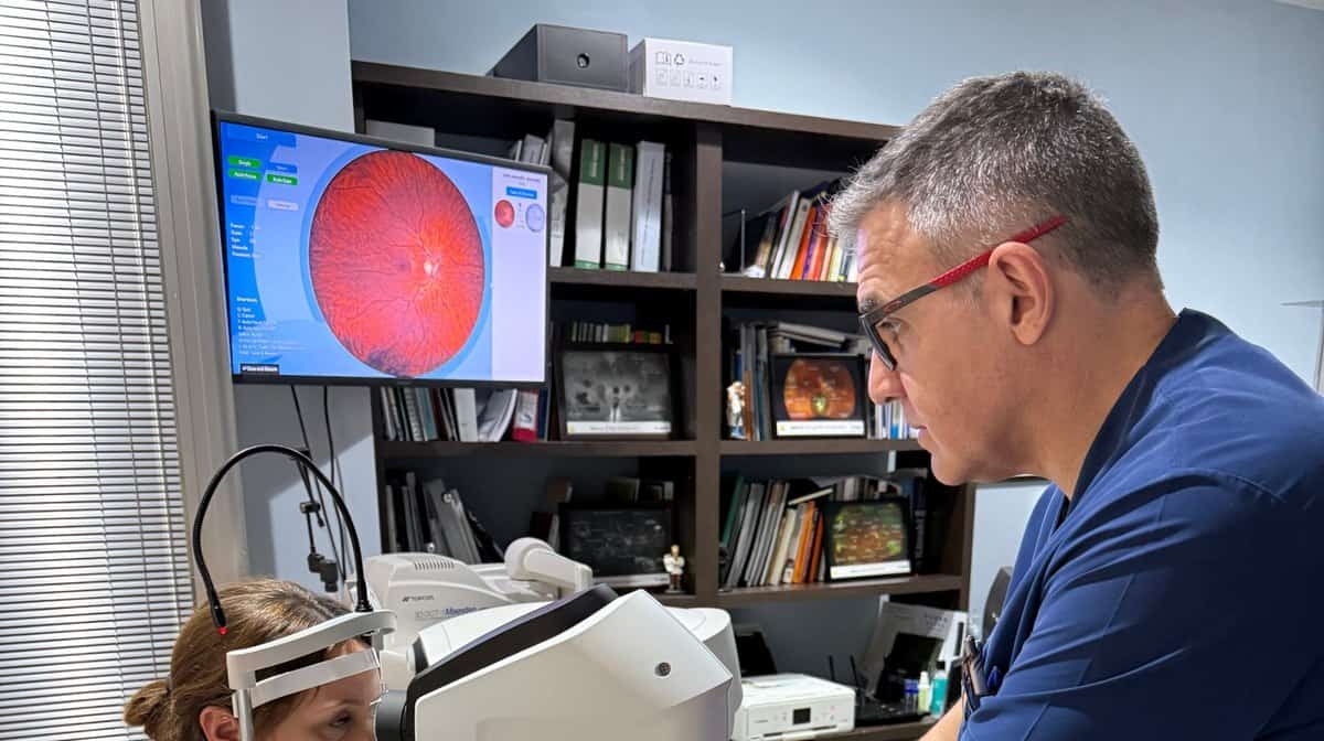 Óptico-optometrista realizando una retinografía de campo amplio a una paciente durante una revisión visual en el Centro Óptico Raga de Linares